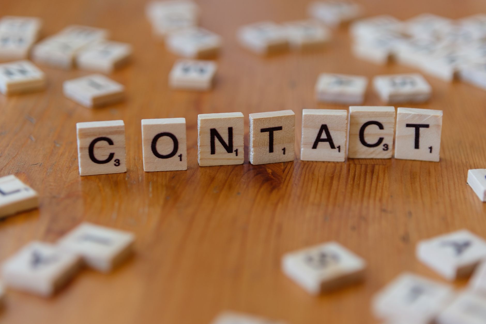 scrabble tiles spelling contact on wooden table